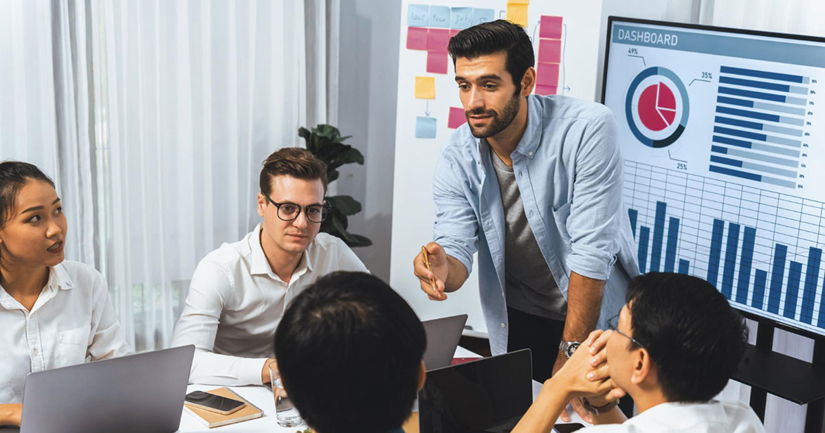 Business professionals collaborating at a meeting table, reviewing documents and charts during a workforce planning discussion.