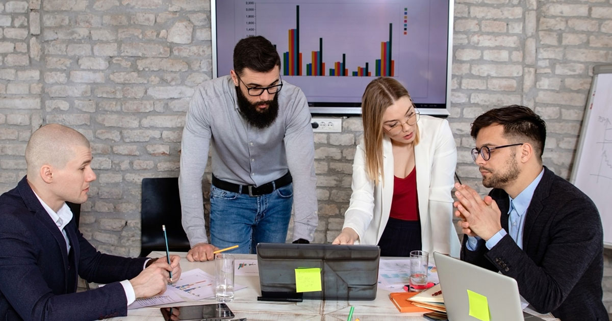 Business professionals collaborating at a meeting table, reviewing documents and charts during a workforce planning discussion.